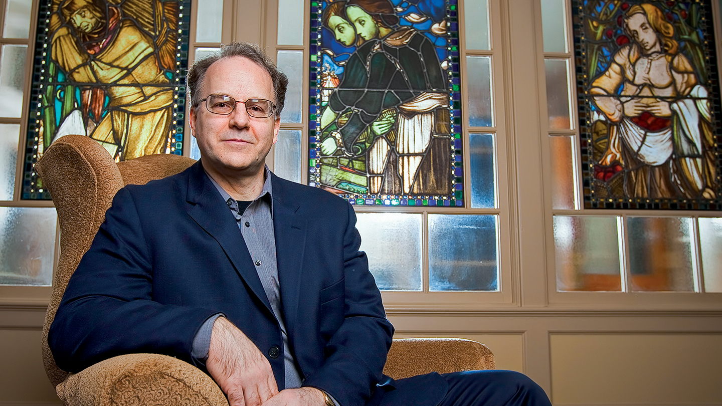 Eric Ziolkowski sits with stained glass artwork behind him