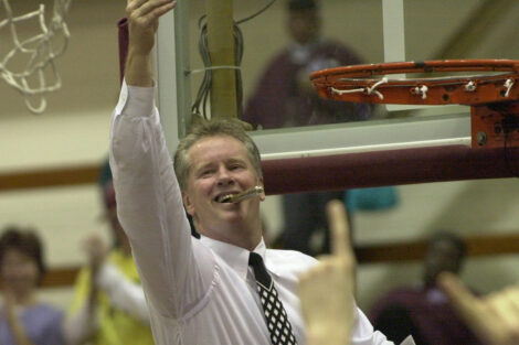 a young Fran O’Hanlon raises his hand and smiles